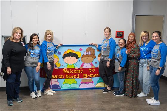A group of women smiling and posing together in a cheerful setting.