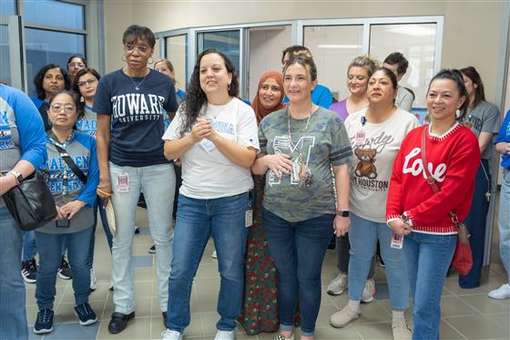 A group of women smiling and posing together in a cheerful setting.