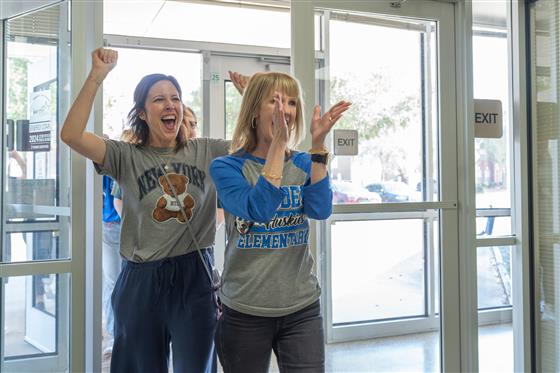 A group of women smiling and posing together in a cheerful setting.